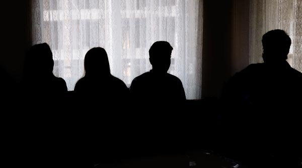 Vier Personen stehen in einem dunklen Raum vor einem Fenster