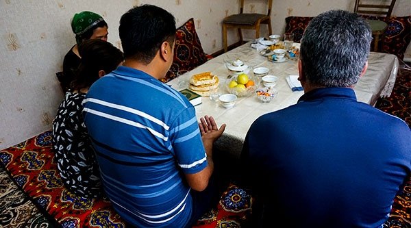 Eine Familie sitzt um einen Esstisch und betet