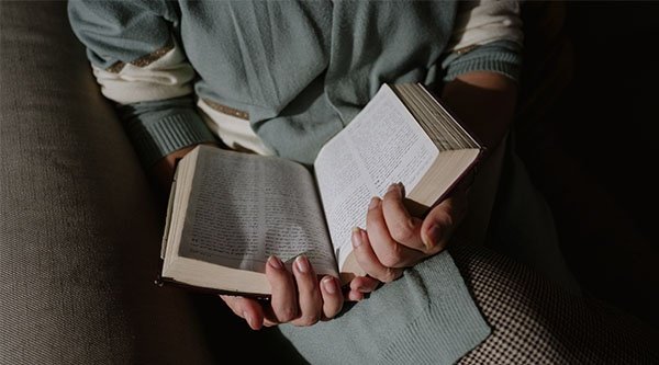 Eine Person hält eine aufgeschlagene Bibel in beiden Händen vor sich.