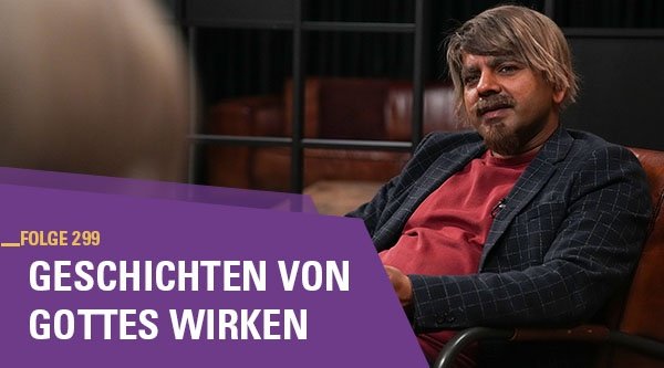 Ein Mann sitzt auf einem Sessel und redet mit jemand