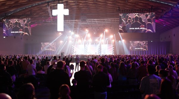 Tausende Jugendliche preisen Gott im Lobpreis beim Open Doors Jugendtag. Tausende Menschen stehen vor einer großen Bühne.
