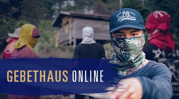 Ein maskierter Mann hält ein Messer in die Kamera