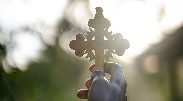 Ein geschnitztes Kreuz wird in die Luft gehalten