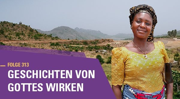 Eine Frau steht in einer Hügellandschaft und lächelt in die Kamera
