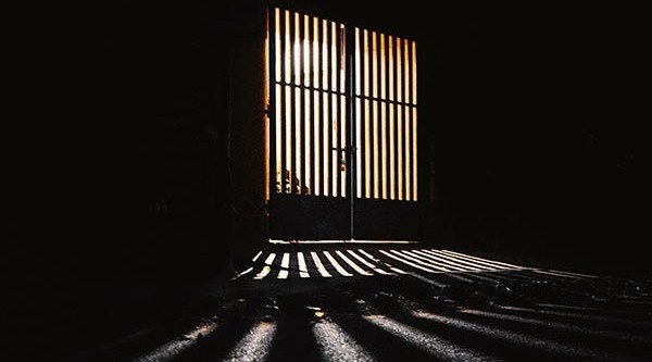 Licht scheint durch eine vergitterte Tür