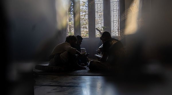 Vier Leute sitzen auf dem Boden einer Kirche in einem Kreis im Dunkeln
