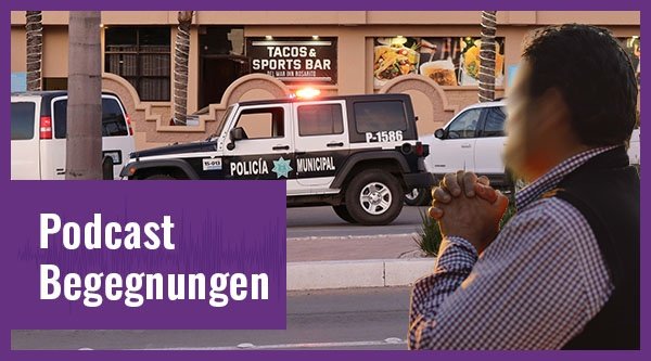 Ein Mann betet vor einem Polizeiwagen