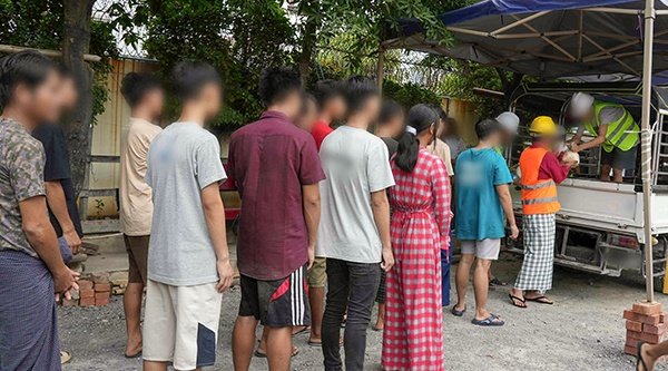 Menschen stehen in einer Schlange vor einem Laster mit Hilfsgütern