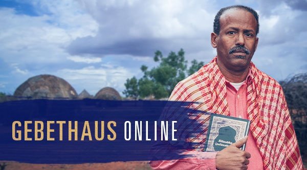 Ein Mann mit einem Buch in der Hand in einem afrikanischen Dorf