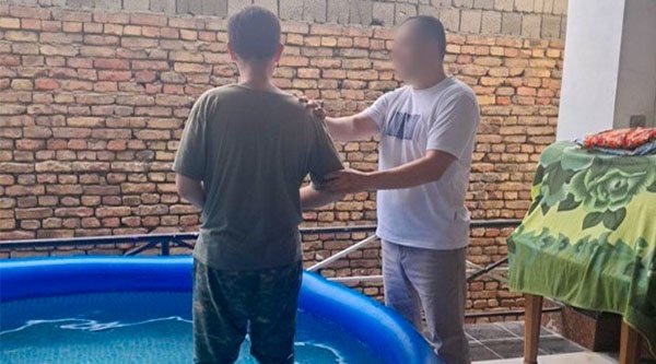 Ein Mann wird von einem anderen Mann in einem Pool getauft.