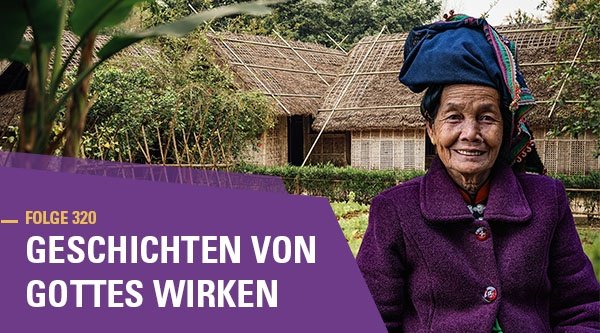 Folge 320 Geschichten von Gottes Wirken | Eine Vietnamnesin in traditioneller Kleidung steht vor einigen Holzhäusern