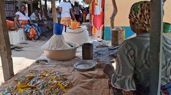 Eine Frau sitzend an ihrem Stand auf dem lokalen Markt.