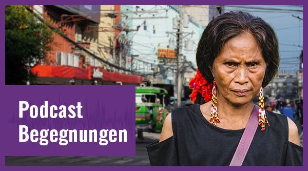 Eine ältere Frau steht an einer belebten Straßenkreuzung. 