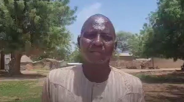 Ein afrikanischer Mann steht vor einem Dorf