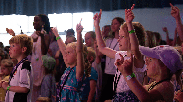 Zahlreiche Kinder beim Lobpreis in einer Messehalle