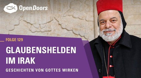 Ein Mann steht mit roter Mütze und schwarzer Jacke draußen vor einer Wand