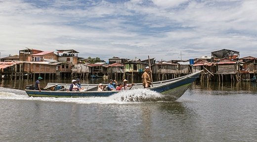 Ein Motorboot mit Menschen darin fährt über einen Fluss
