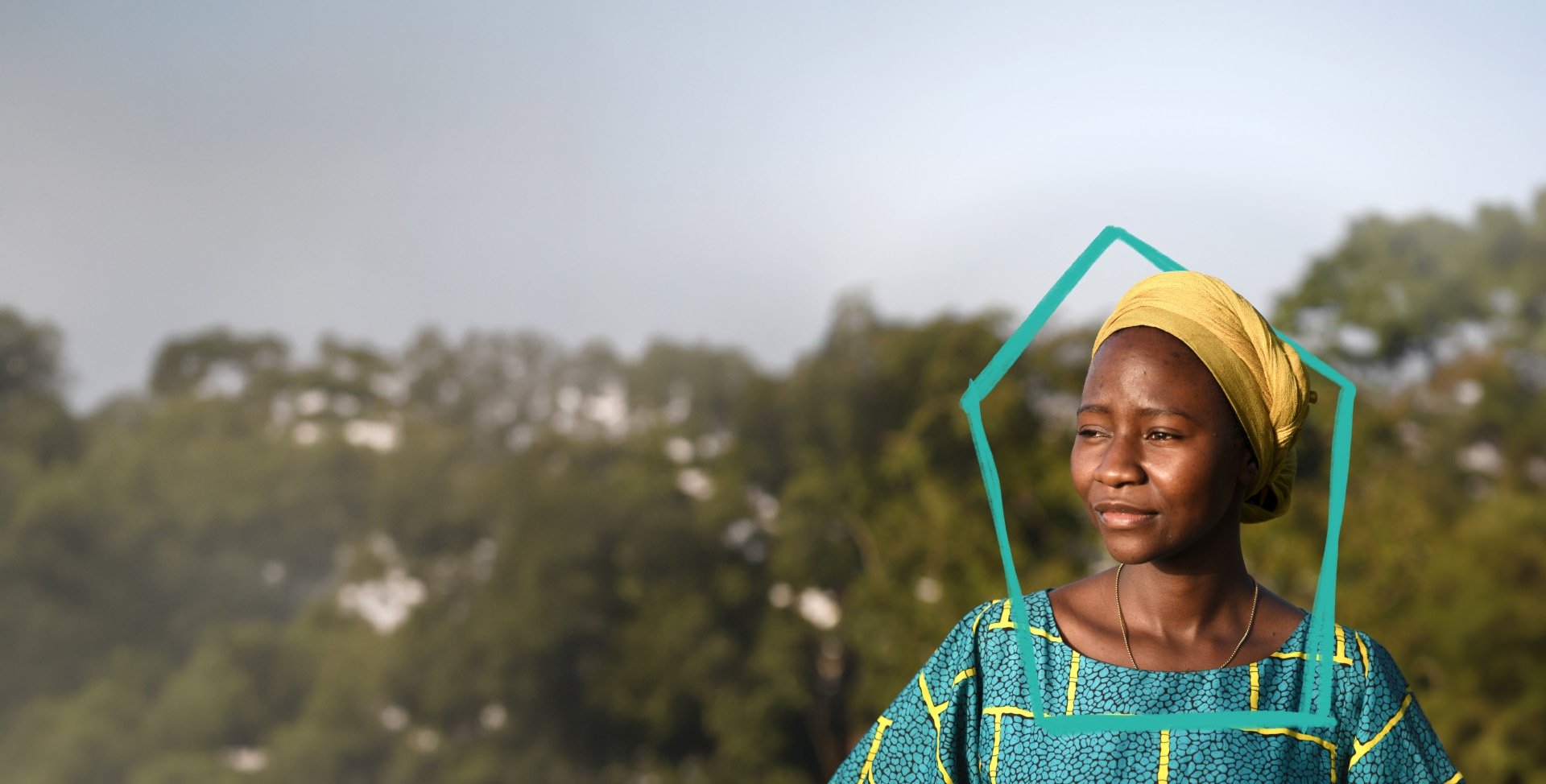 Eine afrikanische Frau in buntem Gewand vor einigen Bäumen