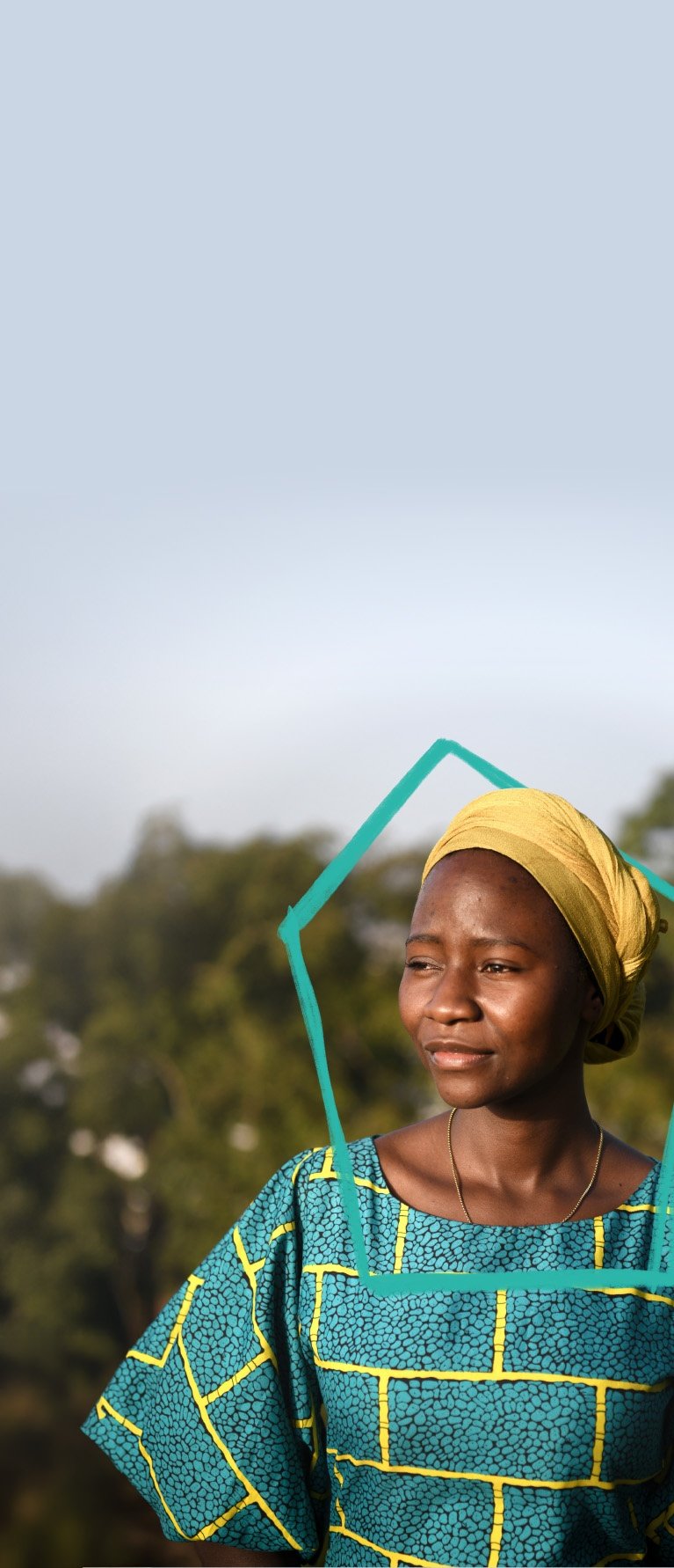 Eine afrikanische Frau in buntem Gewand vor einigen Bäumen