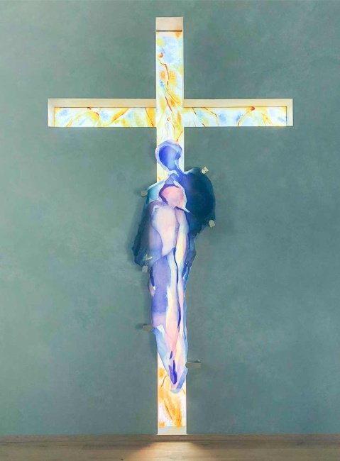 Zwei Glasfiguren stehen vor dem Kreuz: Eine Figur steht leidend, die andere beschirmend – beide verschmelzen, werden eins. Sie bergen sich bei Jesus, dem Auferstandenen und Sieger über Leid und Tod. (Künstlerin der Bilder: Mahbuba Maqsoodi)