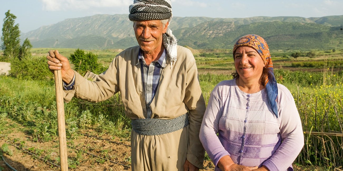 Dieses Ehepaar steht stolz auf seinem Feld, wo es durch Mikrokredite Nutzpflanzen anbauen kann.