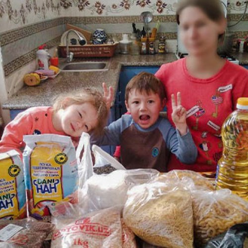 Mutter und zwei Kinder sitzen am Tisch mit Lebensmitteln 