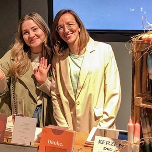 Zwei Frauen stehen an einem Stand mit Kerzen