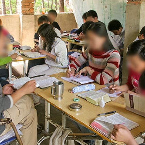 Kinder sitzen an einem Tisch und lesen die Bibel