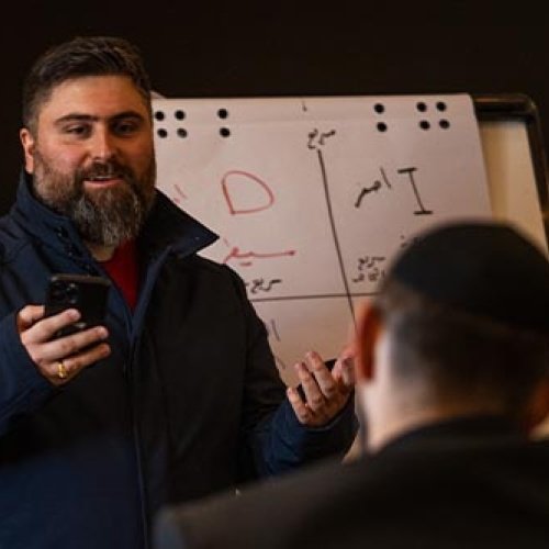 Ein Mann steht vor einer Flipchart und erklärt anderen Männern etwas