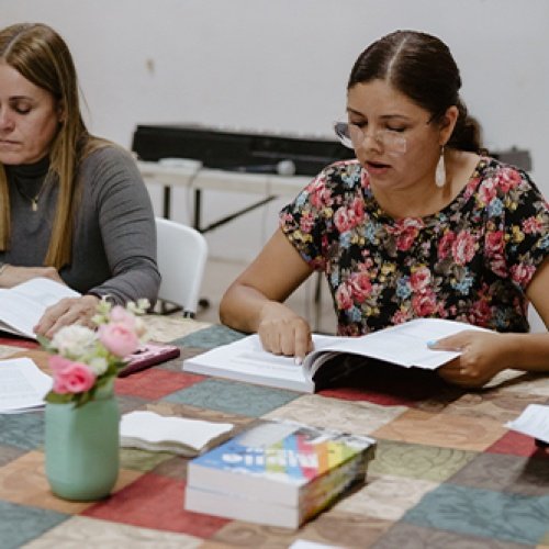 Mehrere Frauen sitzen an einem Tisch und lesen