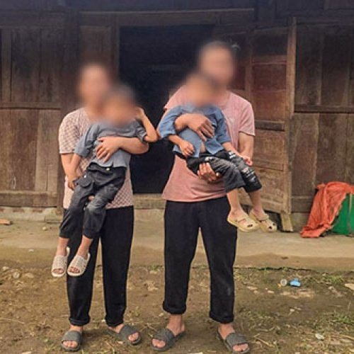 Zwei Erwachsene stehen vor einer Hütte mit zwei Kindern