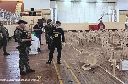 Einsatzkräfte stehen zwischen Trümmern in einer Turnhalle