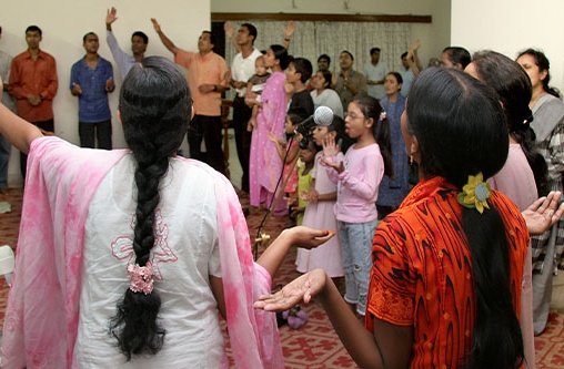 Viele Menschen sind in einem Raum versammelt und heben die Hände