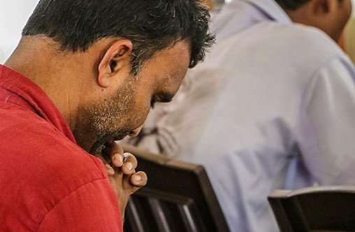 Mann mit rotem T-Shirt betet in einem Gottesdienst