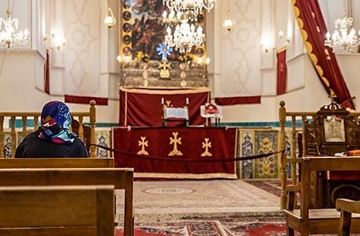 Eine Frau mit einer Kopfbedeckung sitzt in einer Kirche