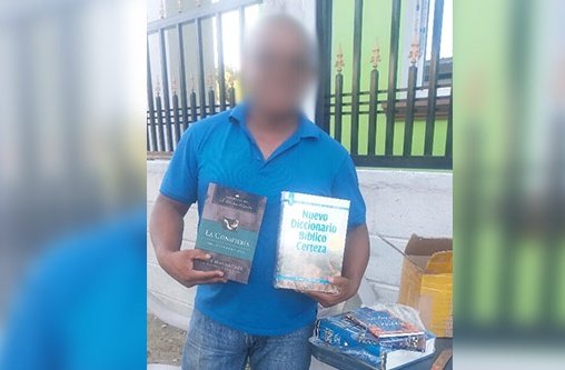 Ein Mann mit blauem Hemd hält Schulungsmaterial in beiden Händen.