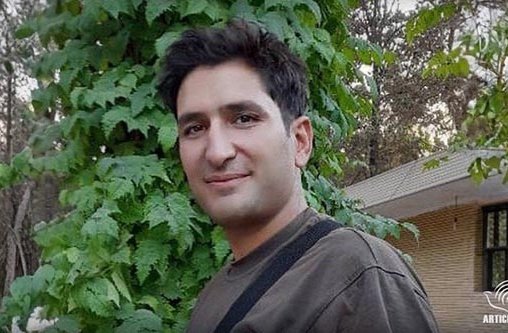 Ein junger Mann steht vor einem Haus im Wald