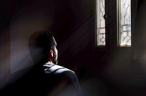 Ein Mann in einem dunklen Raum schaut aus einem Fenster