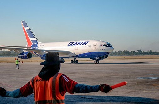 Ein Mann steht am Flughafen und zeigt einem Flugzeug den Weg