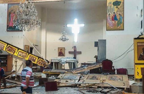 Menschen stehen in einer zerstörten Kirche