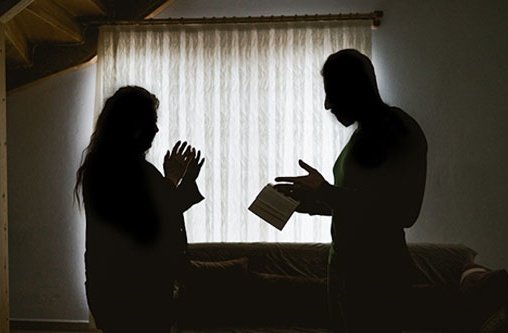 Ein Mann und eine Frau reden in einem dunklen Raum mit einem Buch in der Hand