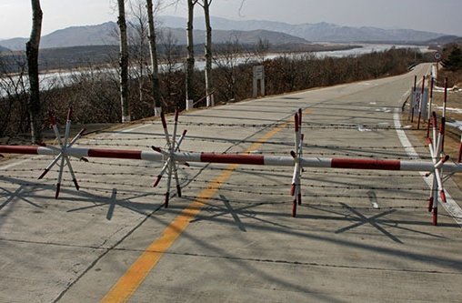 Eine Schranke mit Stacheldraht versperrt eine Bergstraße