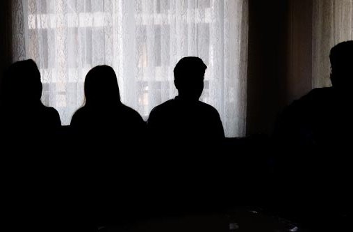 Vier Personen stehen in einem dunklen Raum vor einem Fenster