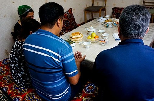 Eine Familie sitzt um einen Esstisch und betet