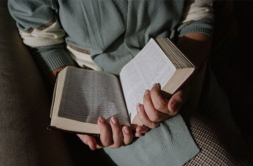 Eine Person hält eine aufgeschlagene Bibel in beiden Händen vor sich.
