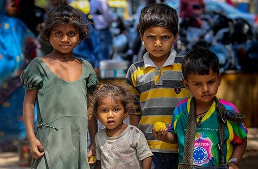 Vier Kinder stehen dicht beieinander und schauen in die Kamera