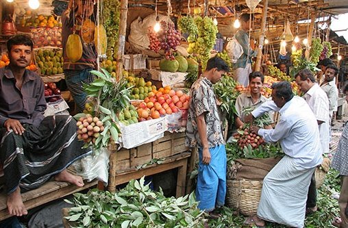 Mehrere Männer stehen an einem Marktstand voll mit Obst