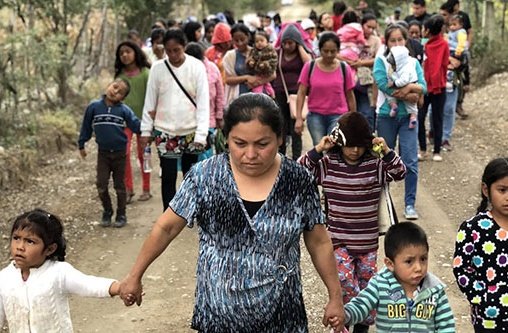 Mehrere Frauen und Kinder laufen auf einer Straße