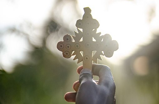 Ein geschnitztes Kreuz wird in die Luft gehalten