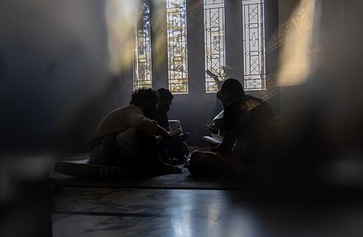 Vier Leute sitzen auf dem Boden einer Kirche in einem Kreis im Dunkeln